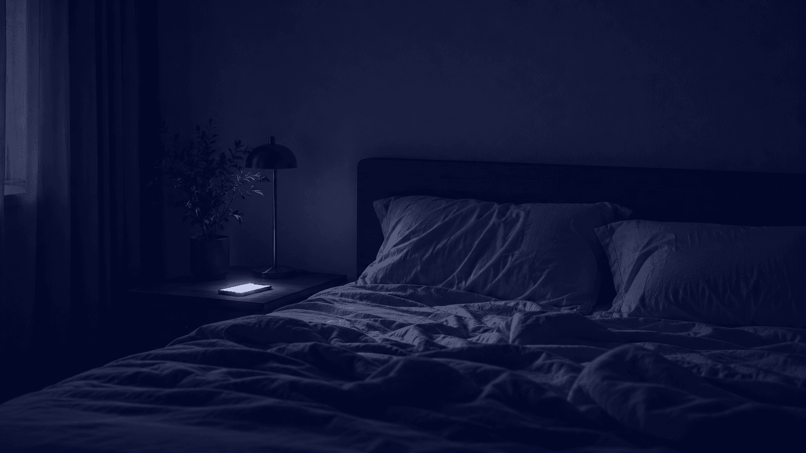A dark bedroom late at night lit only by a phone glowing on the nightstand.